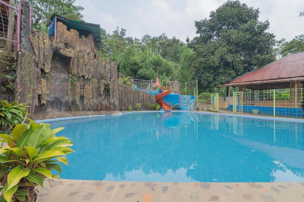 a person is jumping into a swimming pool at RedDoorz Resort Syariah @ Batu Apung Purwakarta in Purwakarta