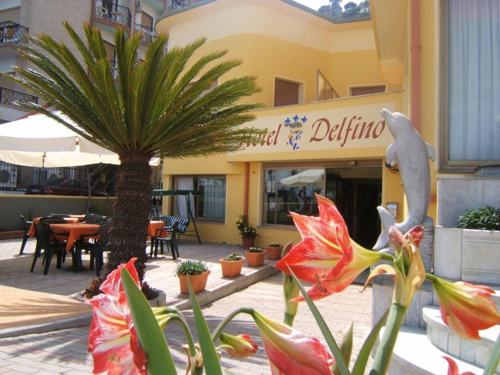 un restaurante con una palmera frente a un edificio en Hotel Delfino, en Laigueglia