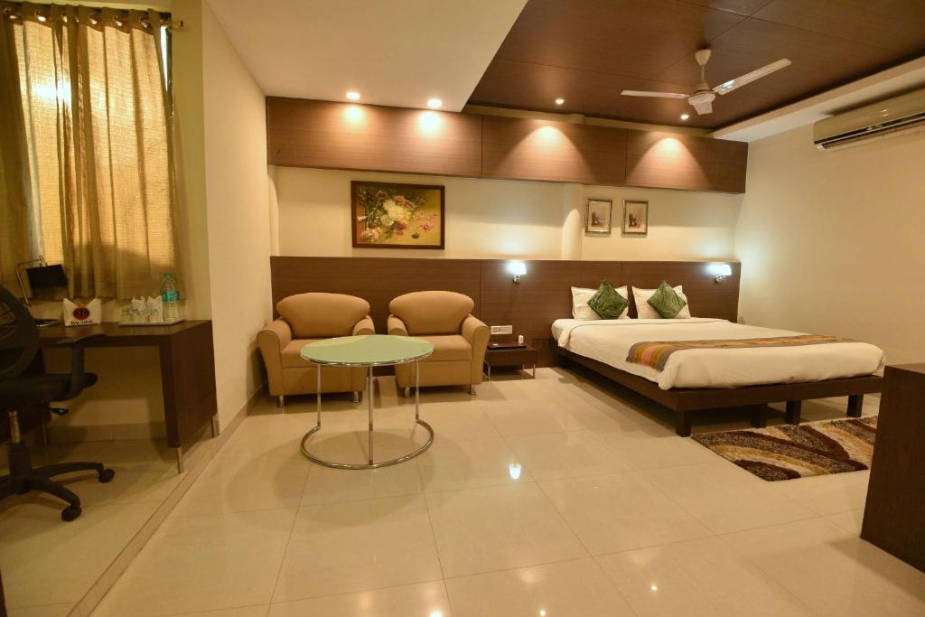 a bedroom with a bed and a desk and a table at Dibrugarh Club House in Dibrugarh