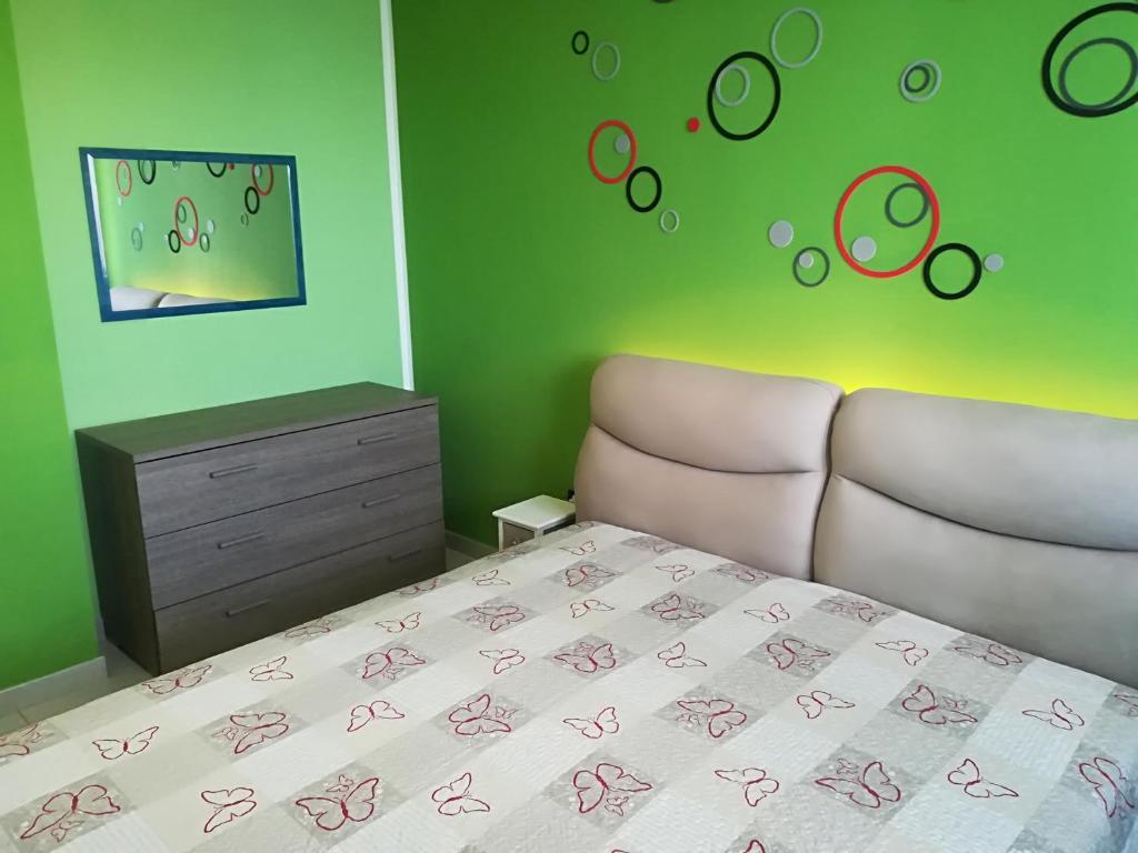 - une chambre avec un lit, une commode et des murs verts dans l'établissement Virginia Otranto holiday home 4 places, à Otrante