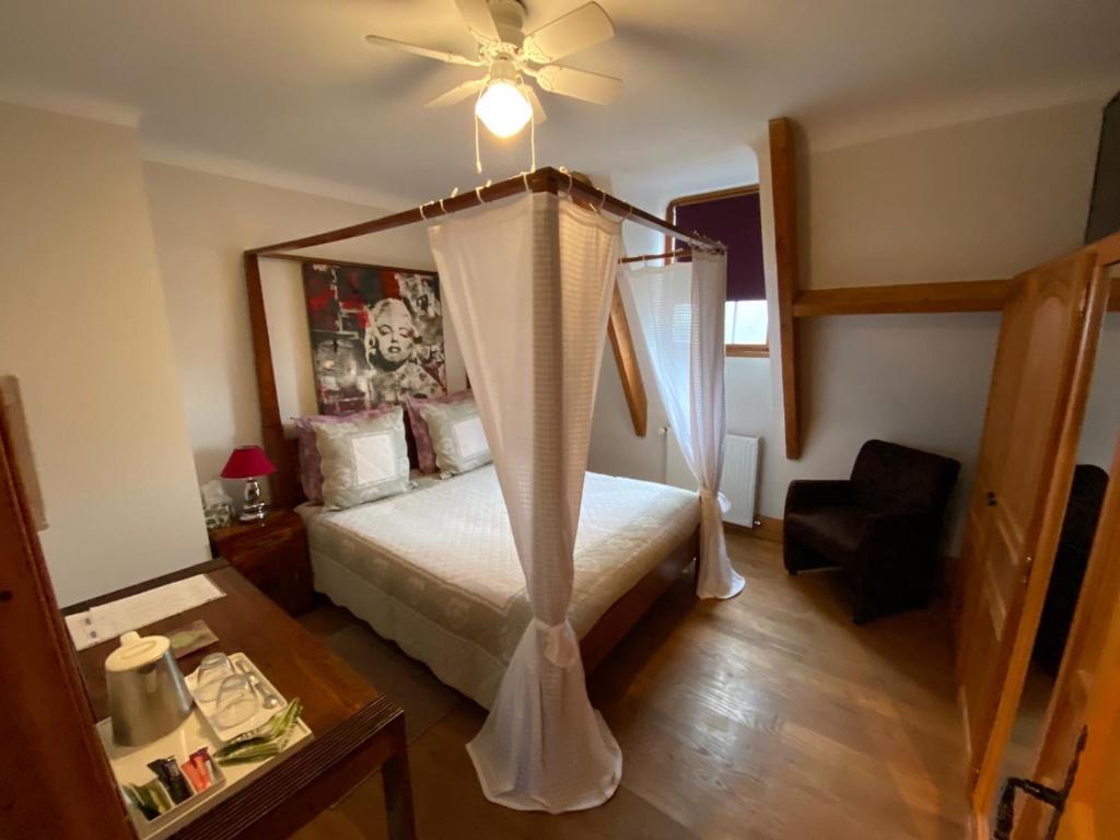 1 dormitorio con cama con dosel y ventilador de techo en Chambres Les Plantous de Severo, en Cénac-et-Saint-Julien