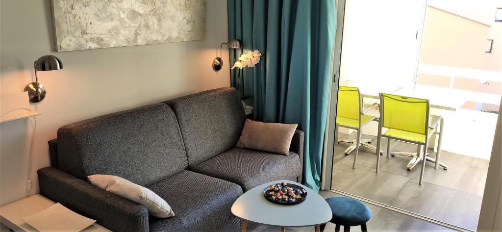 ein Wohnzimmer mit einem Sofa und einem Tisch in der Unterkunft Domaine de La Coudouliere, Vue Mer, Plage, Piscine et Parc in Six-Fours-les-Plages