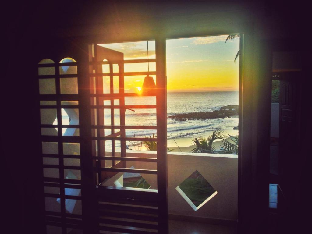 a window with a view of the beach at Villa One64 Beach Front - Apartments in Hikkaduwa
