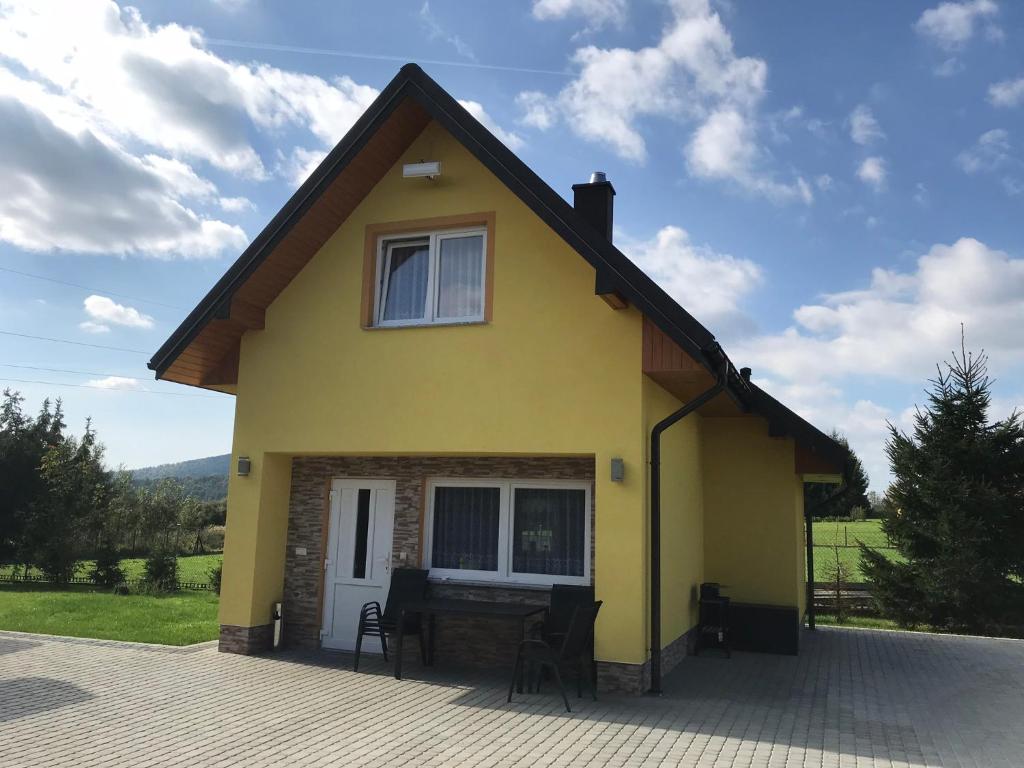 una casa amarilla con una mesa delante en Słoneczny Domek Uherce Mineralne, en Uherce Mineralne