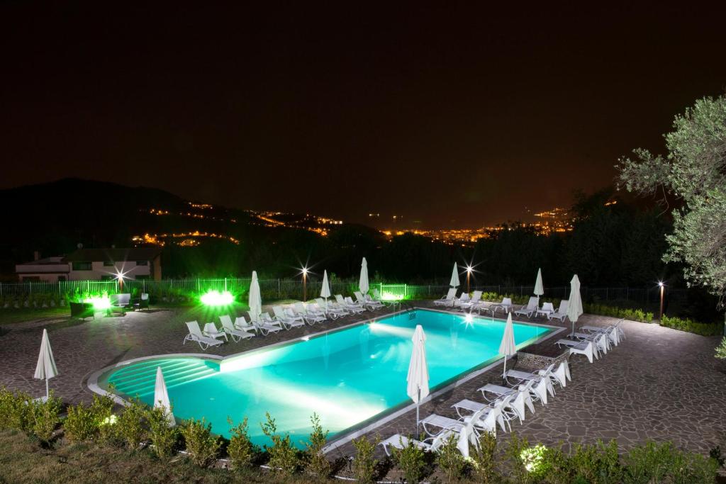 a swimming pool at night with chairs and umbrellas at B&B Villa Setharè in Salerno