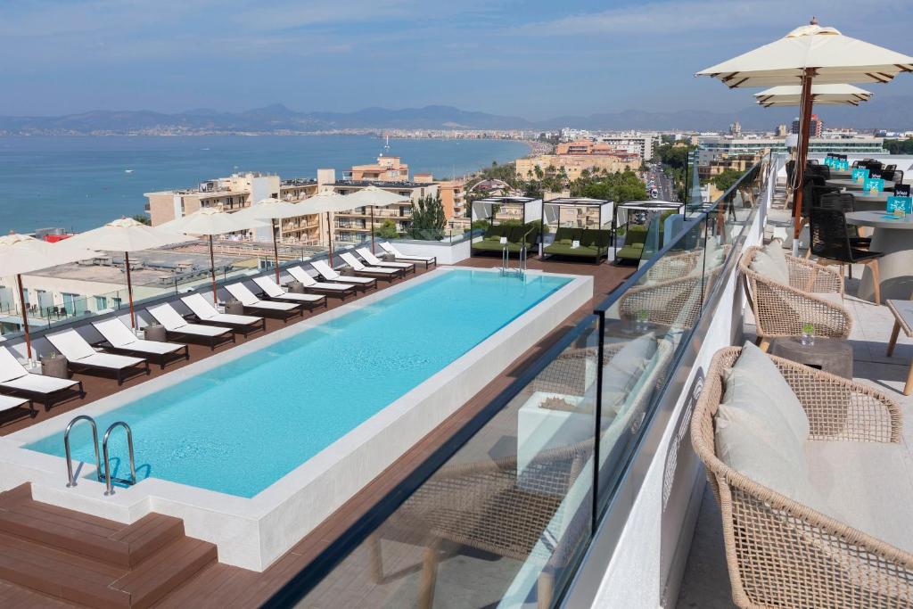 a swimming pool on the roof of a hotel with chairs and umbrellas at HM Ayron Park in Playa de Palma