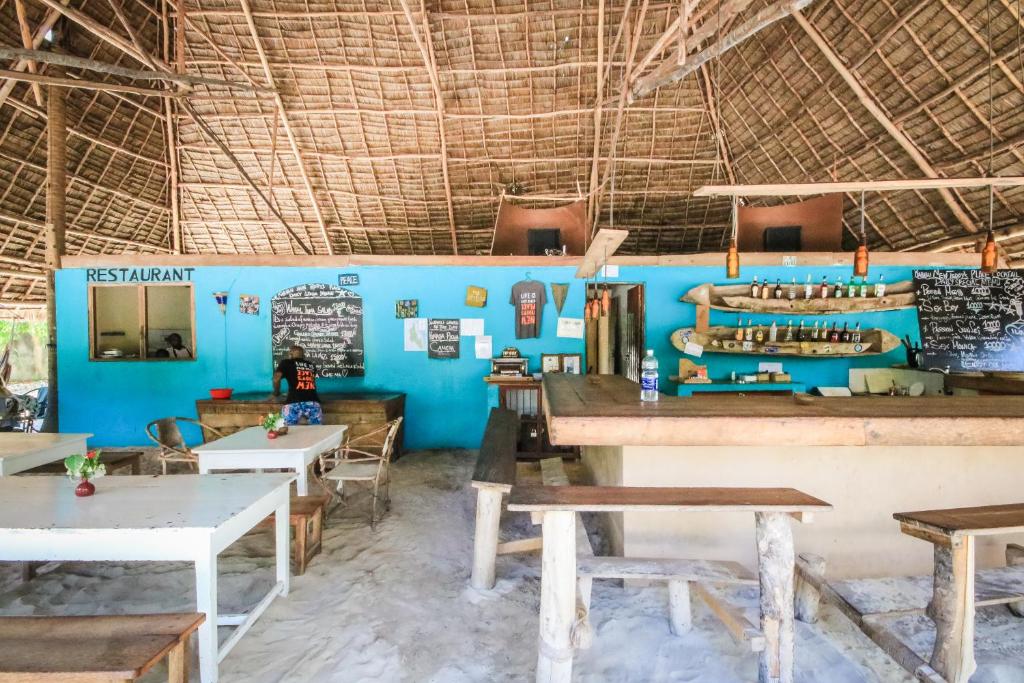 a restaurant with tables and chairs and a blue wall at Your Zanzibar Place in Paje