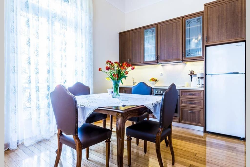 eine Küche mit einem Tisch mit Stühlen und einem Kühlschrank in der Unterkunft Neoclassical apartment with 3 bedrooms in Piraeus in Piräus