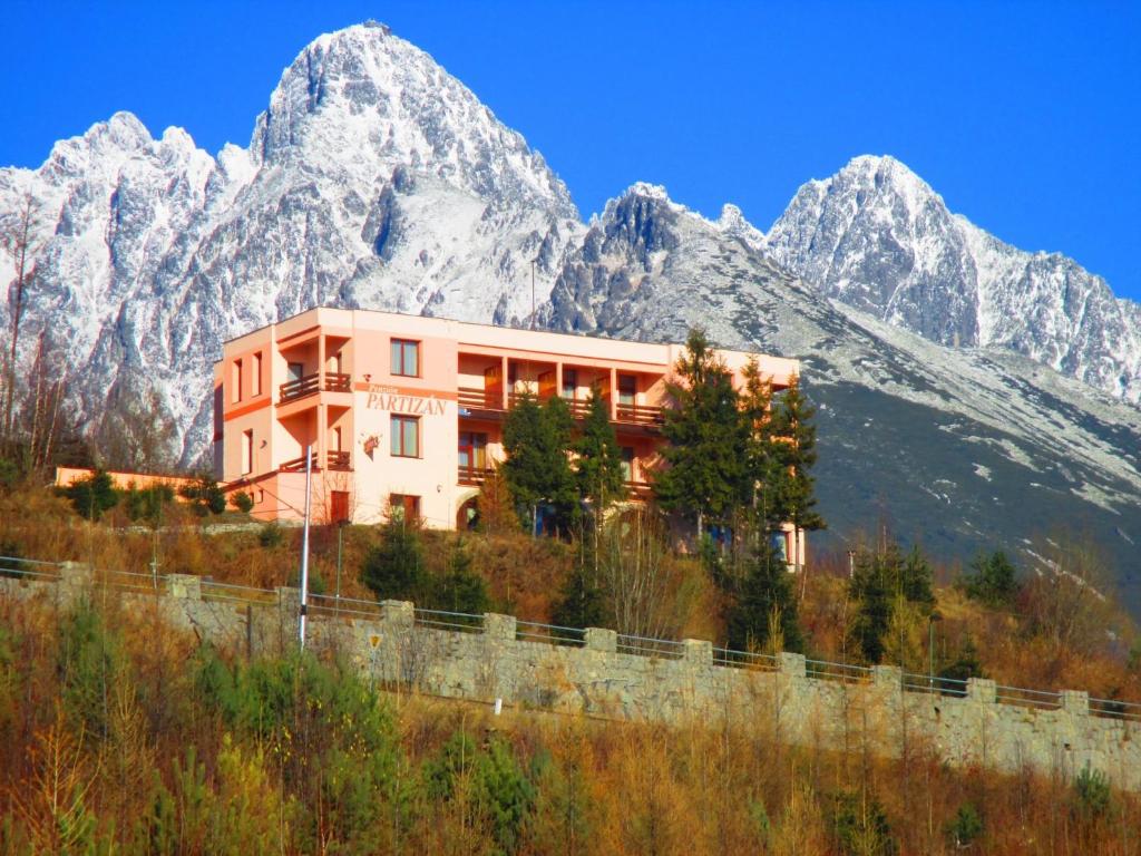 a building in front of a mountain range at Penzion Partizan in Vysoke Tatry - Horny Smokovec