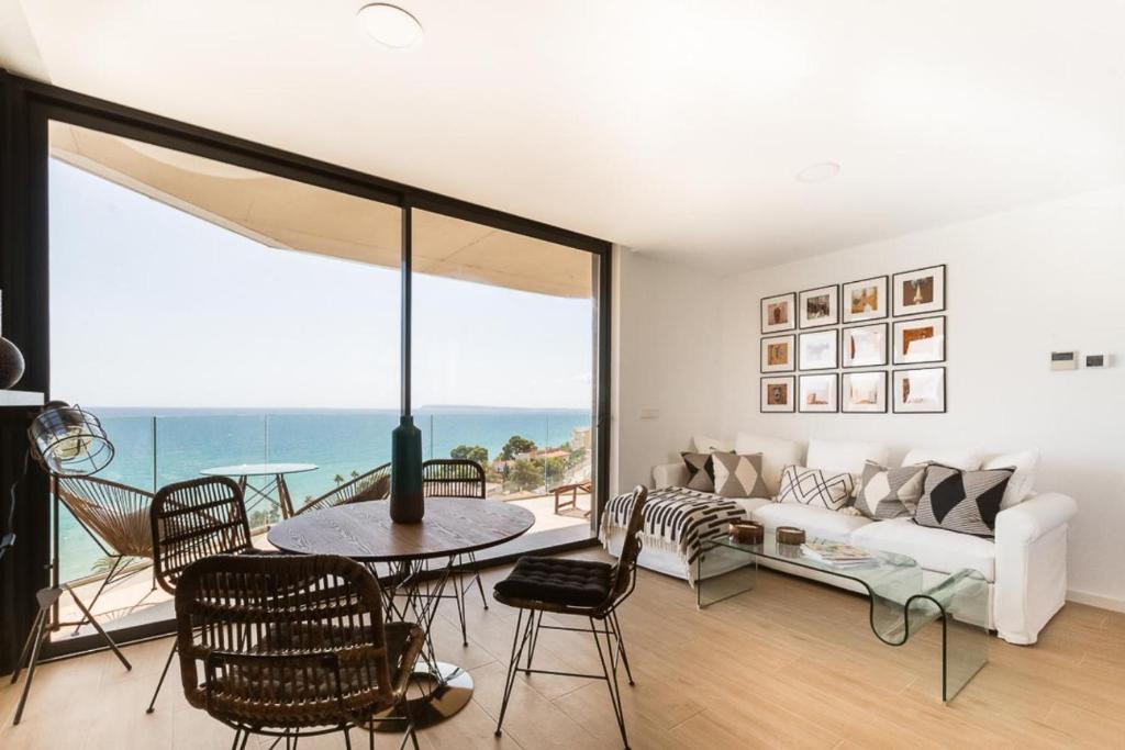 sala de estar con sofá blanco, mesa y sillas en Modern sea front Sea Water, en Alicante