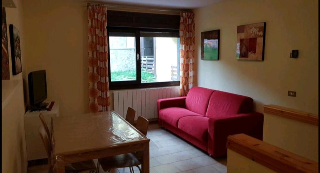 阿貝托內的住宿－trilocale sulle piste da sci，客厅配有红色的沙发和桌子