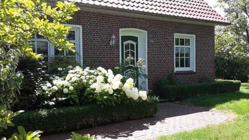 a red brick house with white flowers in front of it at Fehnhaus Janke in Nortmoor