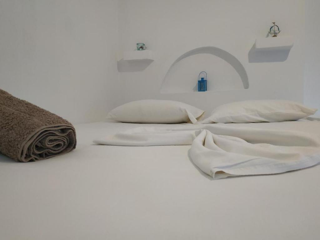 Una cama con sábanas blancas y almohadas. en stamatia's rooms, en Agios Kirykos