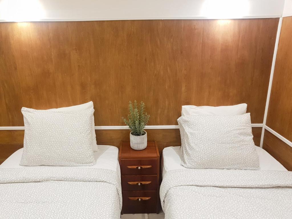 Habitación con 2 camas con almohadas blancas y paredes de madera. en Waves Guesthouse, en San Sebastián