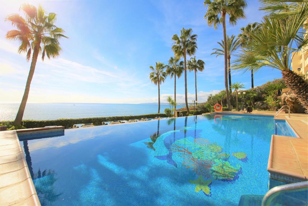 una piscina con palme e l'oceano di Estepona Port Apartment LUNA a Estepona