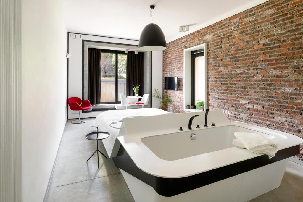 a bathroom with a large white bath tub next to a brick wall at B&B Bed and Beyond in Oudsbergen 