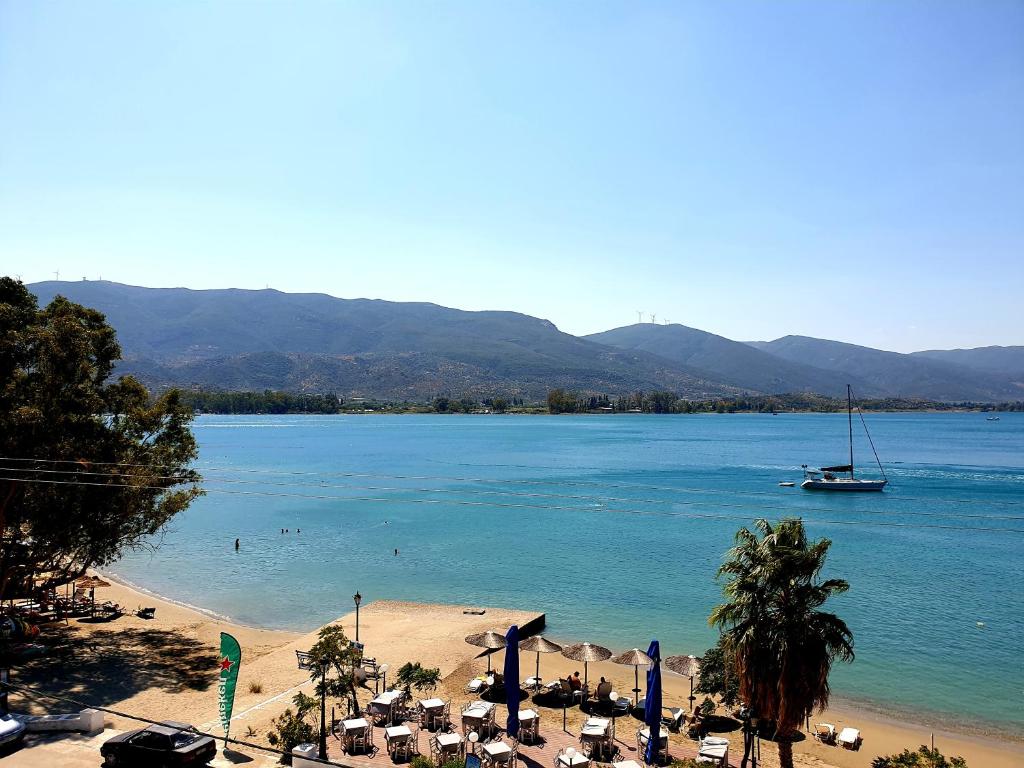 una playa con sombrillas y un barco en el agua en Hotel Pavlou, en Poros