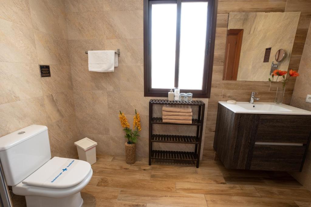 a bathroom with a toilet and a sink and a window at Hostal Casa Mercedes in Nerja