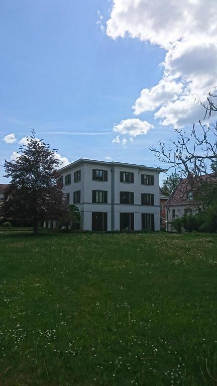 un grand bâtiment blanc dans un champ d'herbe verte dans l'établissement Architekten Villa in Theaternähe, à Meiningen