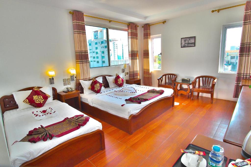 sypialnia z 2 łóżkami, stołem i krzesłami w obiekcie Kaung Myint Hotel w mieście Mandalaj