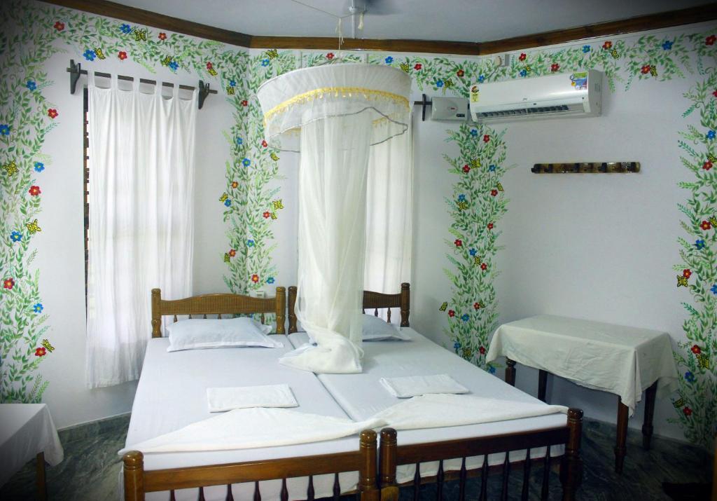 two beds in a room with floral wallpaper at Jickys Nest in Varkala