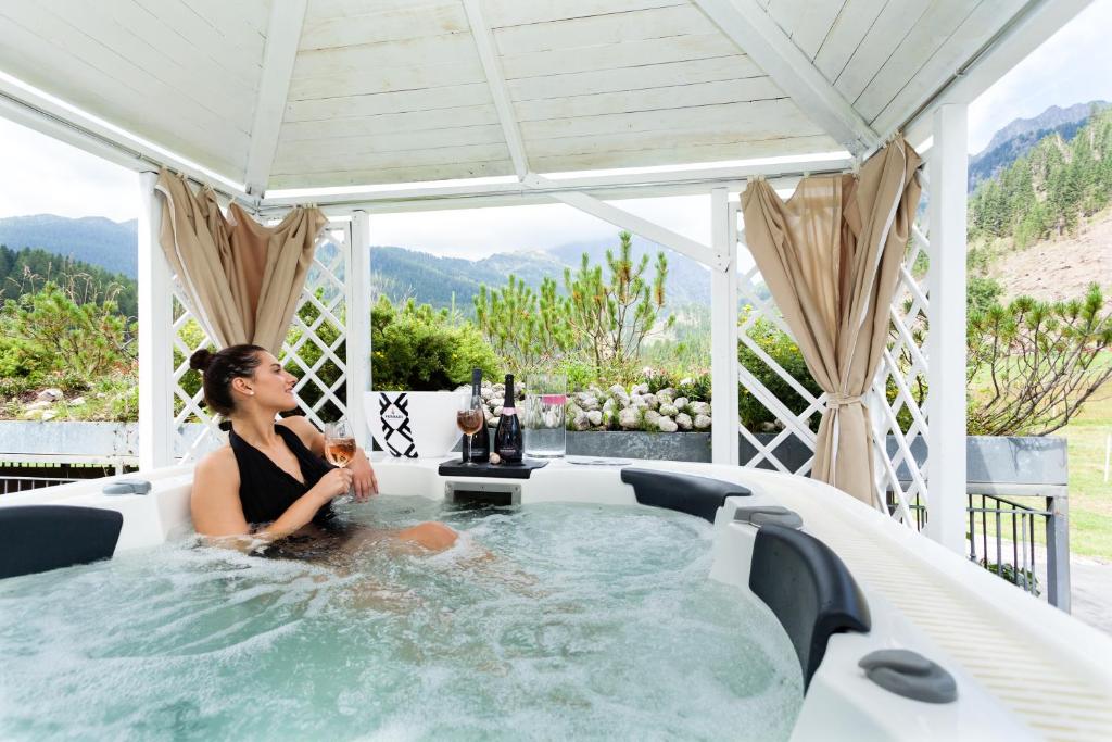 eine Frau, die in einer Whirlpool-Badewanne auf einer Terrasse sitzt in der Unterkunft Hotel Vienna in San Martino di Castrozza