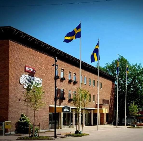 zwei Flaggen vor einem Backsteingebäude in der Unterkunft Hotell Alfred Nobel in Karlskoga