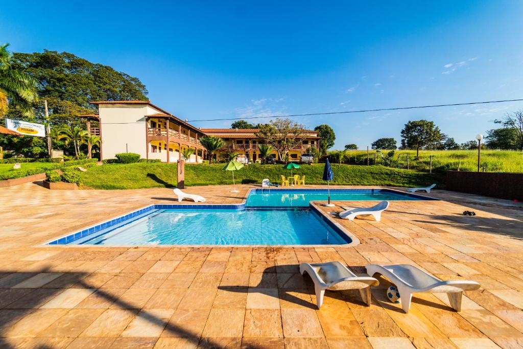 a swimming pool with two chairs and a house at Pousada Doce Rio in Três Marias