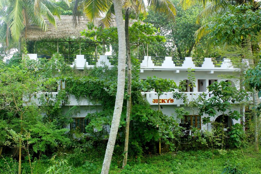 a white building with a sign on it in the jungle at Jickys Nest in Varkala