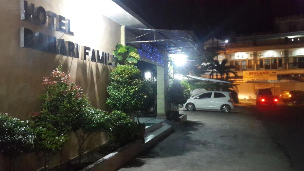 une voiture blanche garée sur un parking la nuit dans l'établissement Bahari Family Hotel, à Bitung