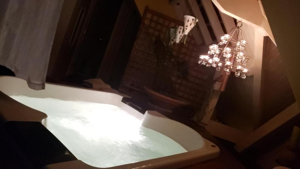 y baño con bañera blanca y lámpara de araña. en Belíssima COBERTURA no Condomínio Switzerland, o conforto que toda família merece, en Campos do Jordão