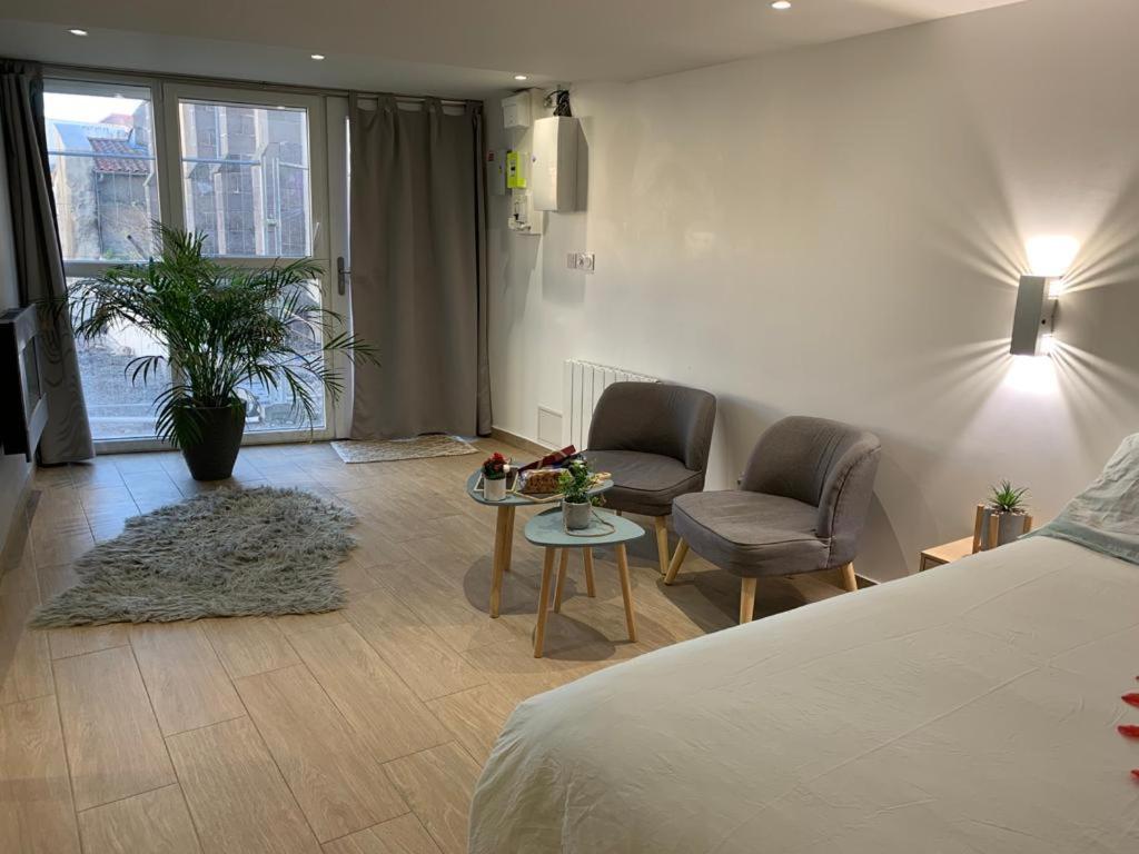 1 dormitorio con 1 cama, mesa y sillas en Le Menhir Jacuzzi Lit 200x200 en Le Cendre
