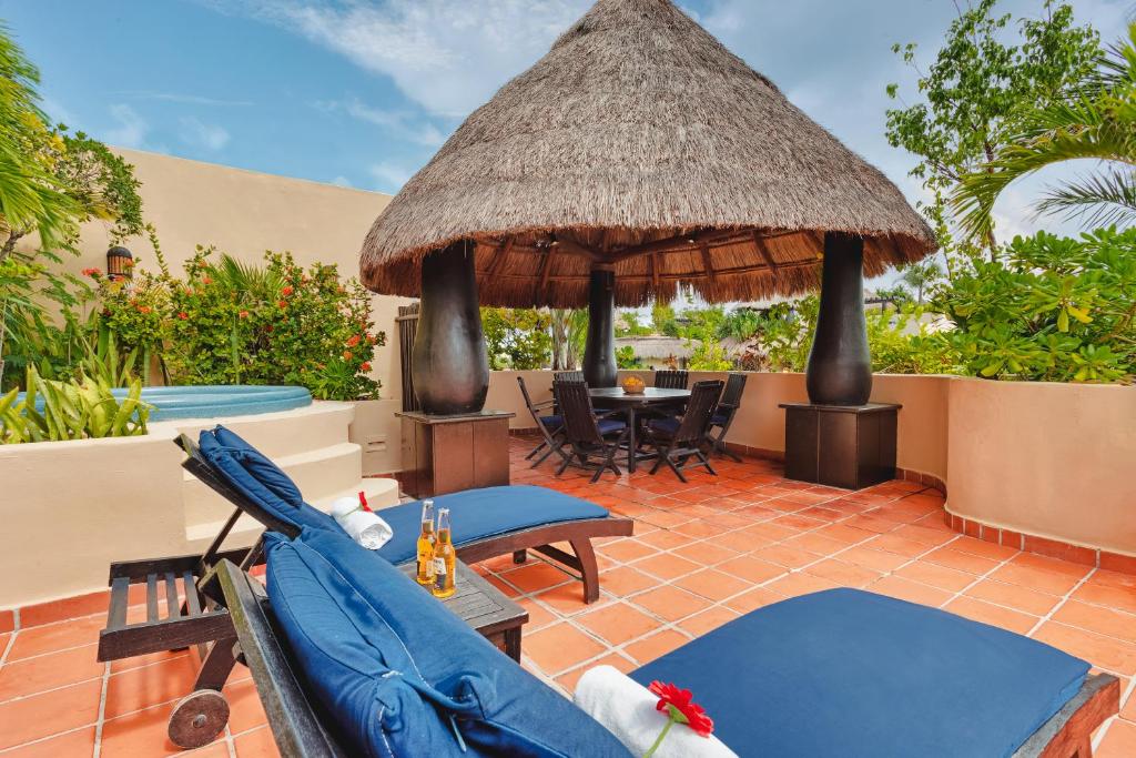 a patio with chairs and an umbrella and a table at El Taj Oceanfront and Beachside Condo Hotel in Playa del Carmen