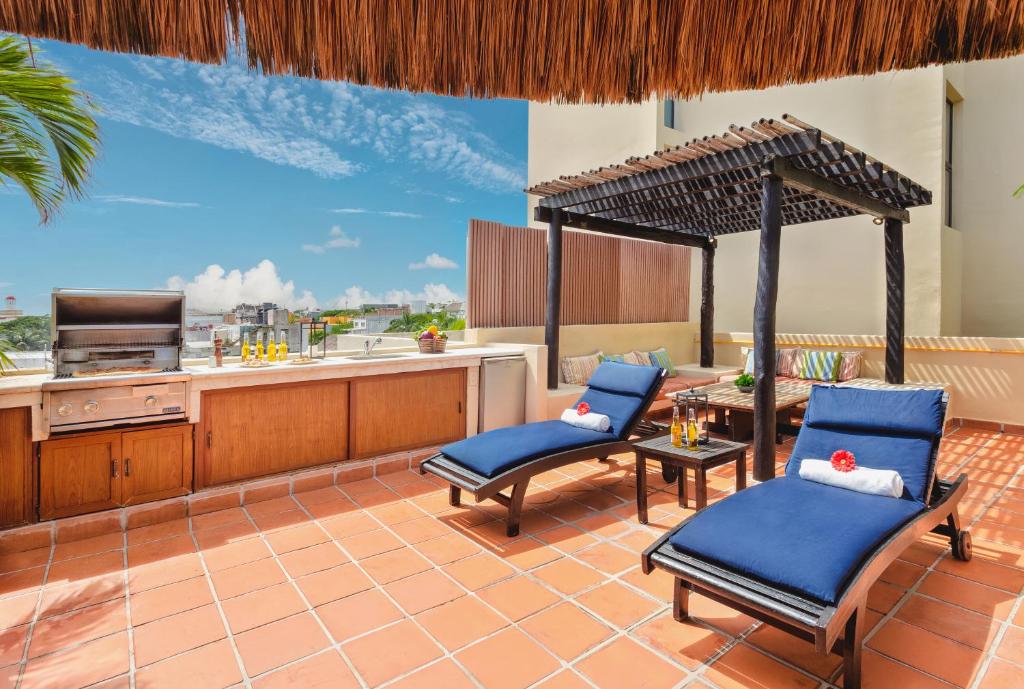 a patio with two blue chairs and a kitchen at El Taj Oceanfront and Beachside Condo Hotel in Playa del Carmen