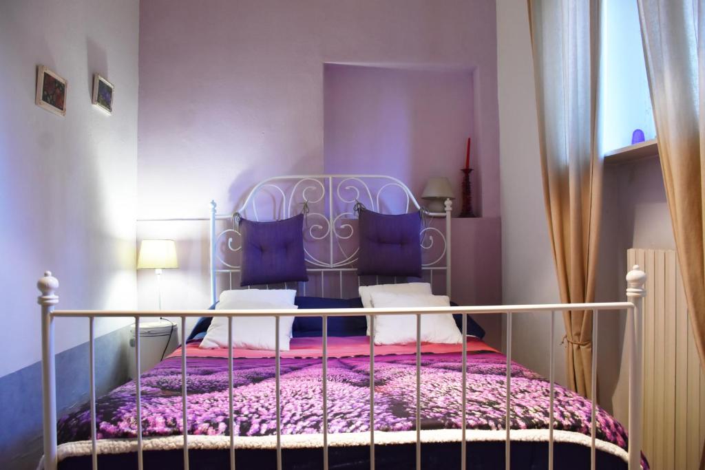 una camera da letto con letto in metallo con lenzuola viola e cuscini blu di B&B via Roma a Bernate Ticino
