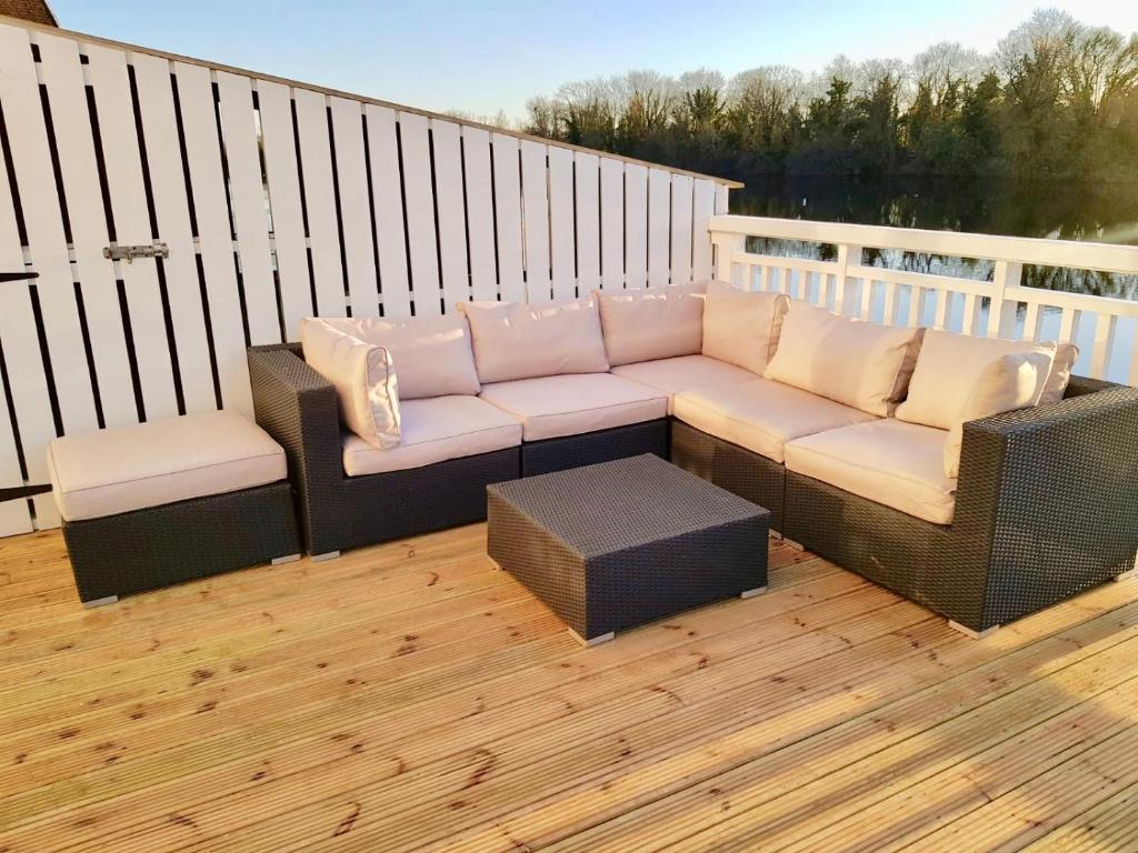 a patio with a couch and chairs on a deck at Nola Lodge in Cirencester