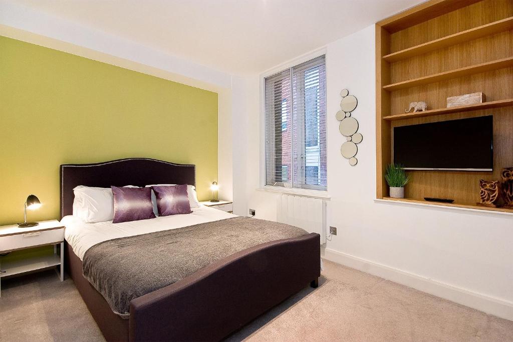 a bedroom with a bed and a flat screen tv at Mulberry Flat 3 - One bedroom 2nd floor by City Living London in London