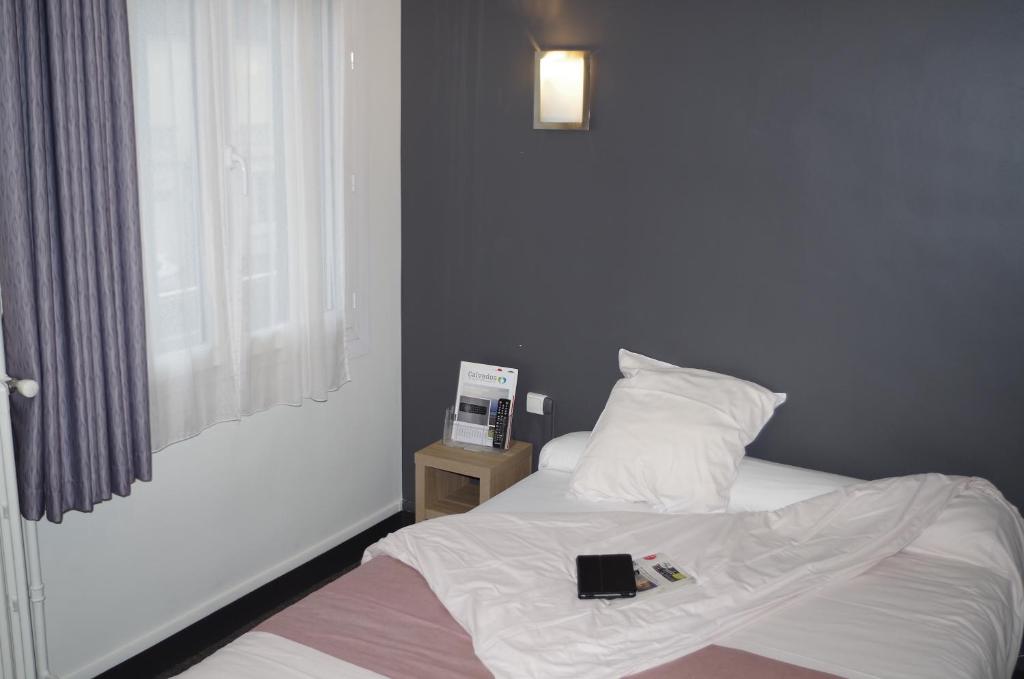 a bedroom with a bed with a book on it at The Originals City, Hôtel Le Savoy, Caen (Inter-Hotel) in Caen