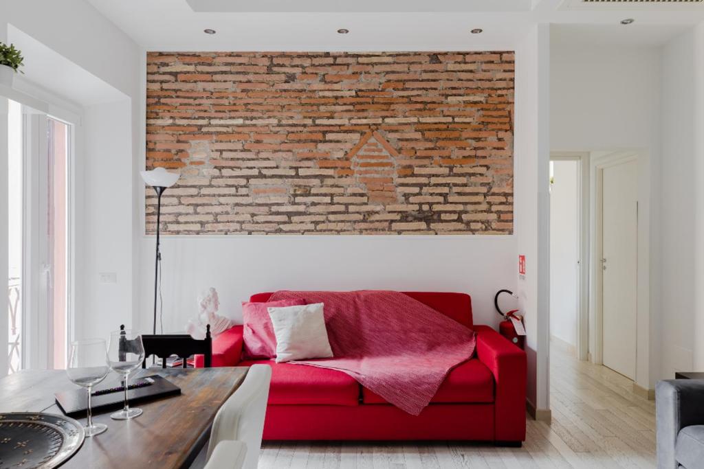 ローマにあるミネルヴァズ プレイスのレンガの壁のリビングルームに赤いソファ