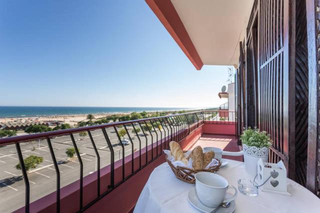 a table on a balcony with a view of the beach at Apartamento Vintage Frente ao Mar in Monte Gordo