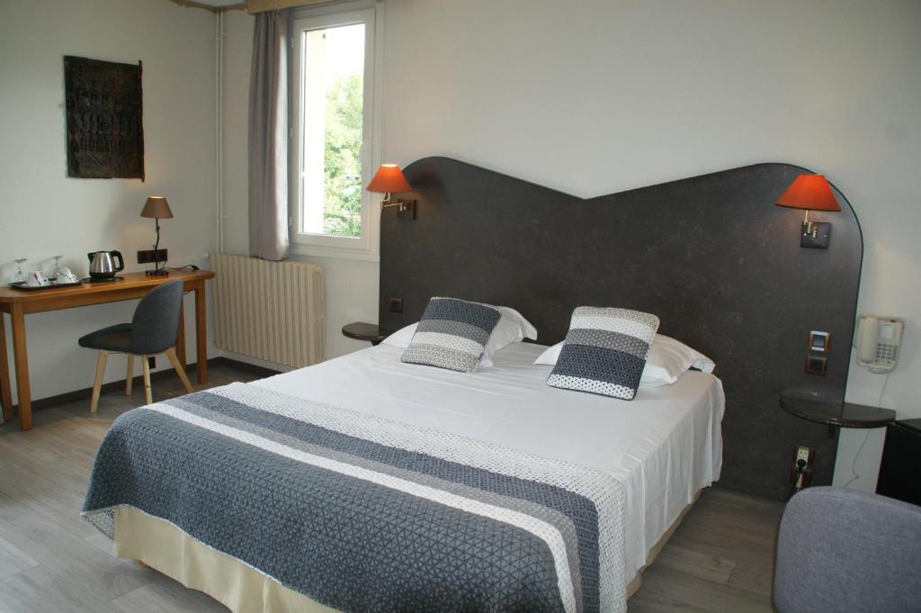 a bedroom with a large bed and a desk at Hôtel L&#39;Iroko The Originals City in Aix-les-Bains