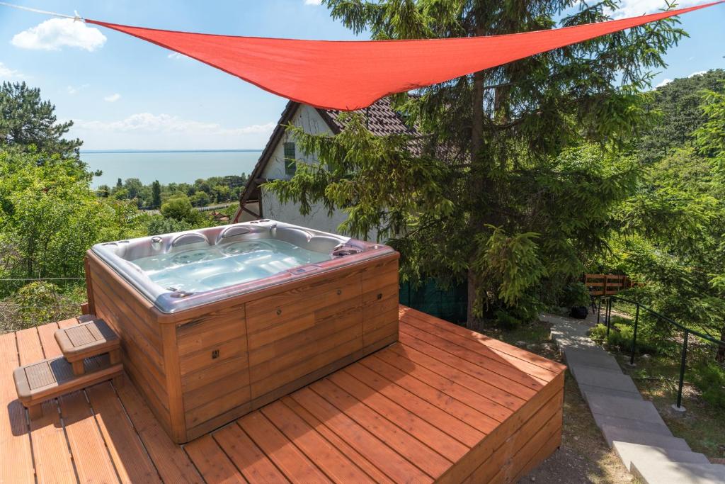 a hot tub on a wooden deck with a red canopy at So&oacute;s Villa Balaton in Balatongy&ouml;r&ouml;k