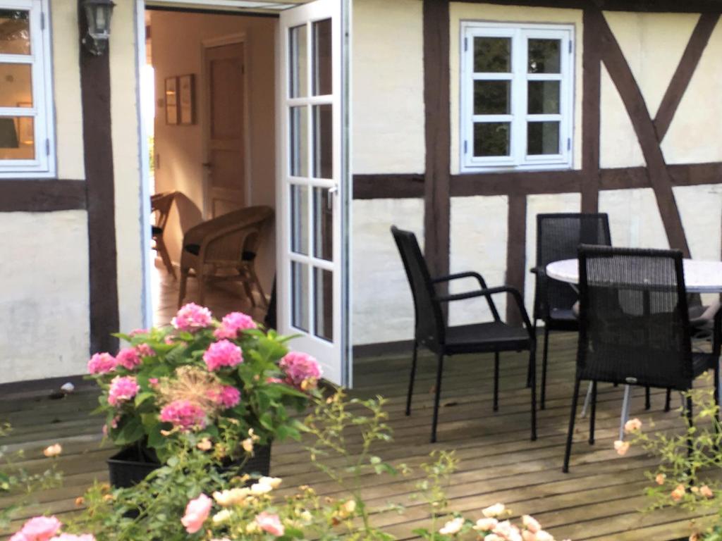 weranda z krzesłami, stołem i kwiatami w obiekcie Ferielejlighed på Rødkærgård w mieście Kerteminde
