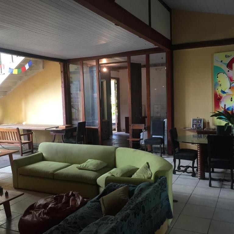 a living room with a green couch and a table at Casa com natureza in Rio de Janeiro