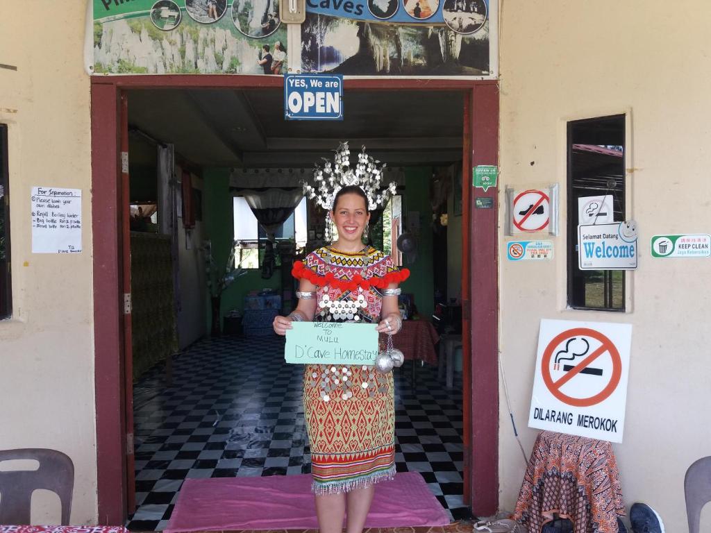 Eine Frau, die in einer Tür steht und ein Schild hält. in der Unterkunft Room 2 in Gunung Mulu Nationalpark