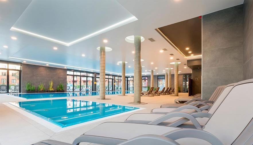 a pool in a hotel with chairs and a swimming pool at Apartament C003 Polanki Park in Kołobrzeg