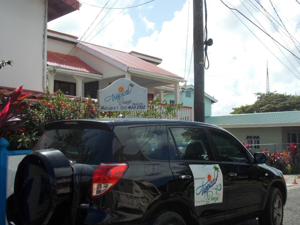 a black car parked in front of a building at Tropical Breeze Vacation Home and Apartments in Gros Islet