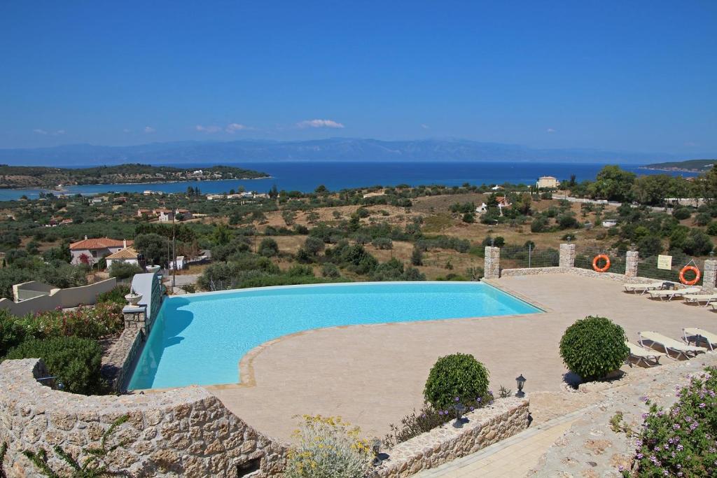 einen Pool auf einem Hügel mit dem Ozean im Hintergrund in der Unterkunft Porto Panorama in Porto Heli