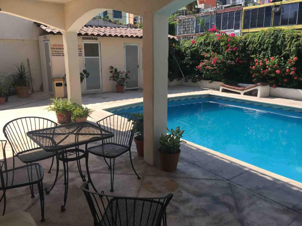 Hotel magallanes con cocineta 100 Metros de playa في أكابولكو: فناء مع طاولة وكراسي بجوار حمام سباحة