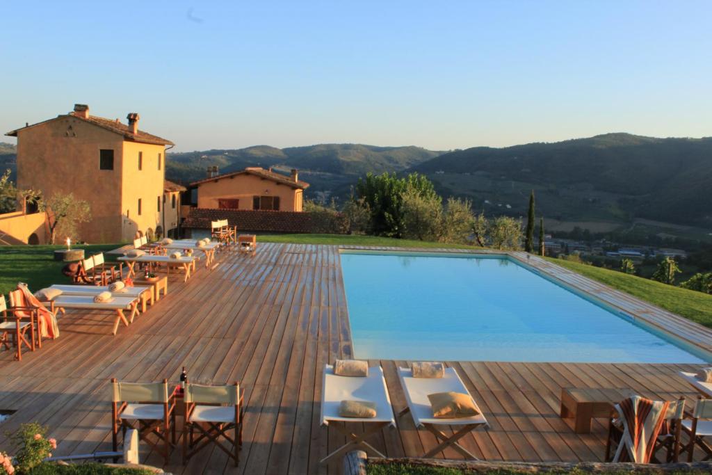 a large swimming pool on a wooden deck with chairs at I Veroni - Agriturismo and Wine Cellar in Pontassieve